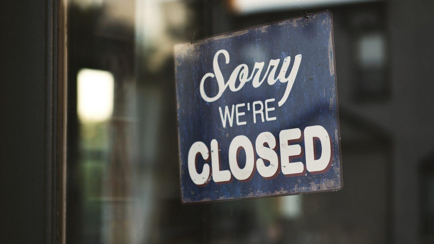 A 'Sorry we're closed' sign behind a glass door