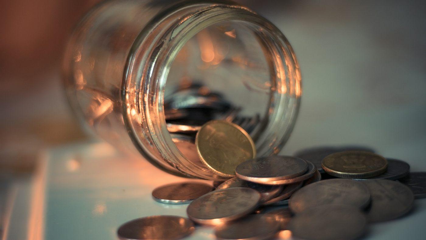 Coins spilling from a tipped-over glass jar