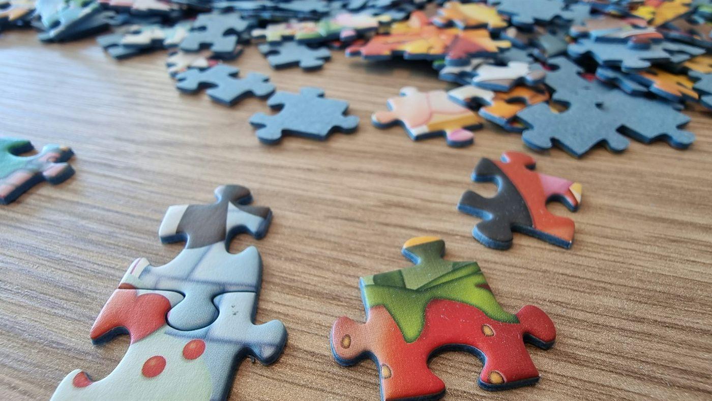 Jigsaw puzzle pieces scattered across a wooden table