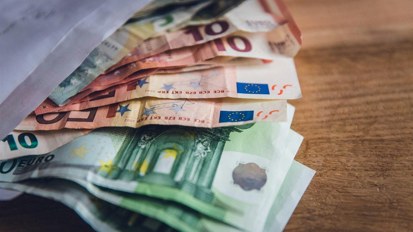 Een stapel eurobiljetten op een houten tafel