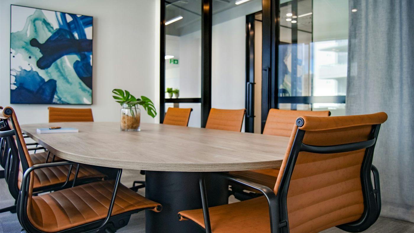 Een vergaderruimte met een ovale tafel en oranje stoelen
