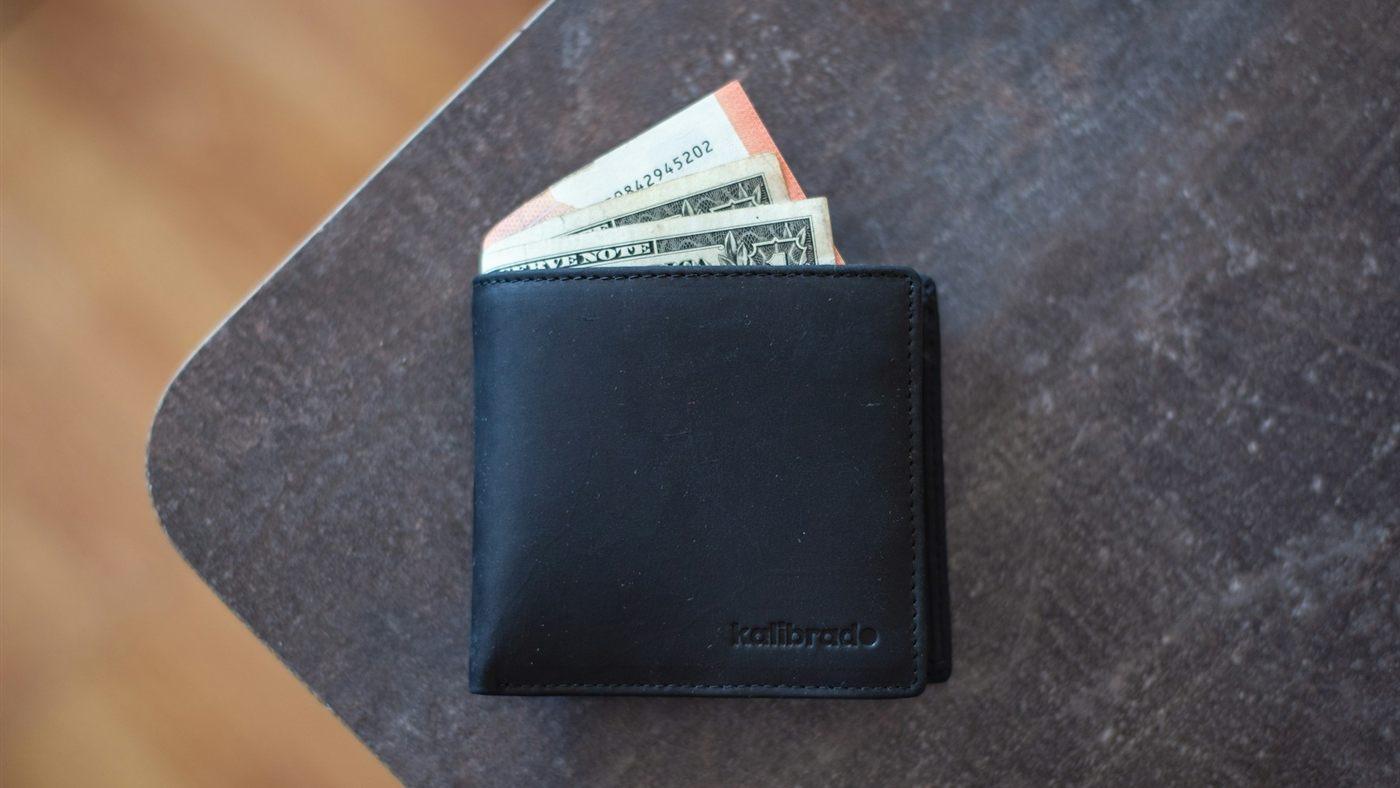 A black wallet with banknotes on a table