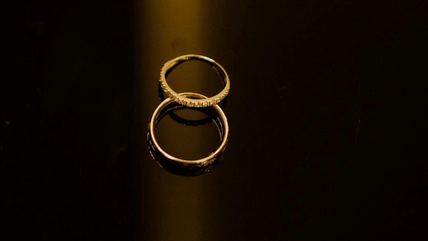 Two gold rings on a dark surface